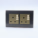 Dark Grey Plastic Arc Double Frame with gold Interests of both Switched UK sockets